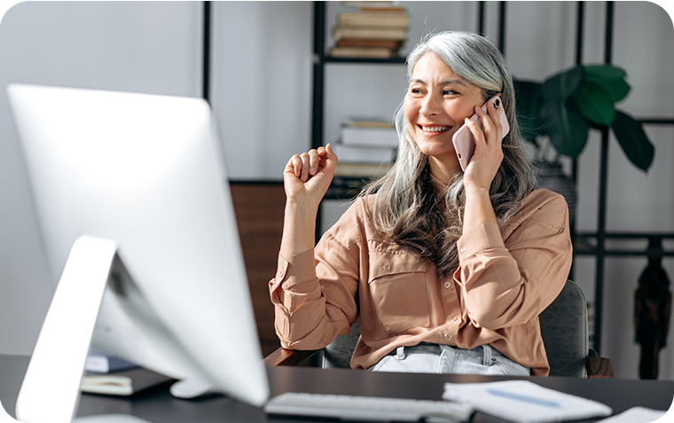 older woman sitting a desk talking on phone