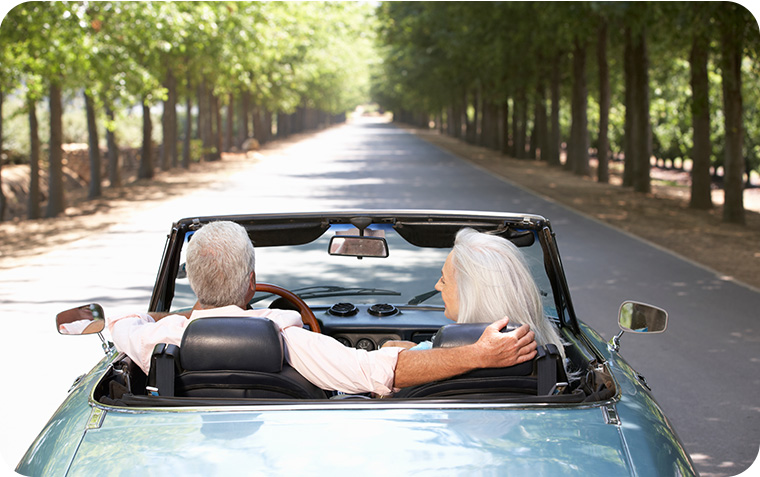 Back view of a retired couple driving down a road with trees on both sides
