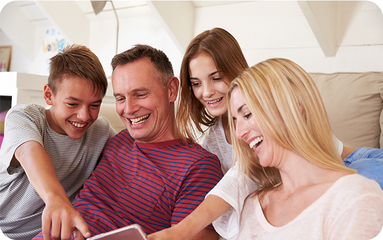 Family huddles together sitting down looking at iPad