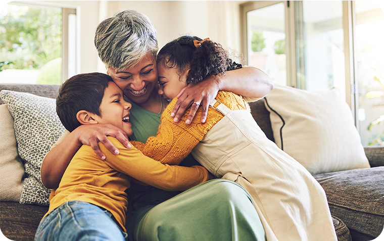 Grandmother on couch hugging grandchildren